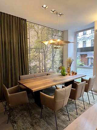 Ausgestellter Essbereich mit Holztisch, Sitzbank und Fototapete mit Waldmotiv.