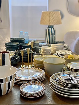 Keramikgeschirr und Schalen auf einem Holztisch im Schauraum.