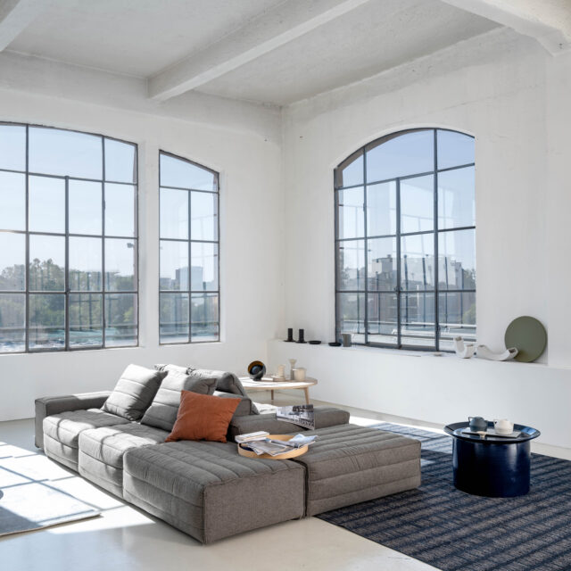 Wohnzimmer mit Modulsofa in grau und Couchtische von Gervasoni
